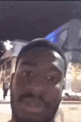 a man with a beard is making a funny face in front of a building at night .
