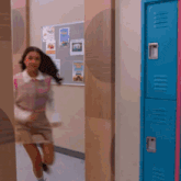 a girl is running through a hallway with a blue locker