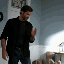 a man in a black shirt is standing in a room with boxes