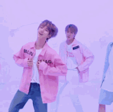 a man in a pink jacket is dancing in front of a purple wall .