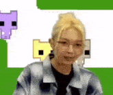 a woman wearing glasses and a plaid shirt is smiling in front of a pixelated background .