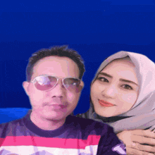 a man and a woman pose for a picture with a blue background