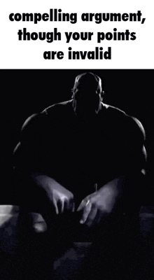 a man with a beard is sitting in a chair with his hands folded in front of him .