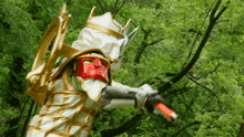 a person in a white and gold costume is holding a red stick in front of trees