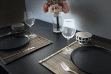 a place setting with plates glasses and a vase of flowers