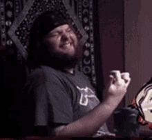 a man with a beard is sitting in front of a tapestry with the number 6 on it