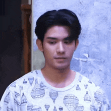 a young man wearing a shirt with hot air balloons on it .