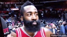 a basketball player with a beard is being interviewed by a reporter in front of a crowd