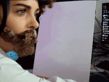 a man with a fake beard is sitting in front of a computer screen