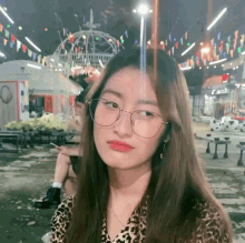 a girl wearing glasses and a leopard print shirt is looking at the camera