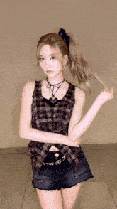 a woman wearing shorts and a plaid shirt is standing in front of a wall