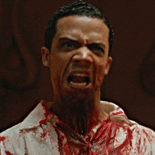 a man with blood on his shirt and neck is making a funny face