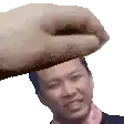 a hand is holding a man 's head in front of his face .