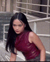 a woman in a red sleeveless top is standing on a set of stairs