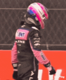 a race car driver wearing a pink helmet and a black jacket with the word afnl on it