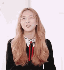 a woman with long blonde hair is wearing a black dress with a red tie
