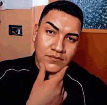 a man has his hand on his chin and looks at the camera