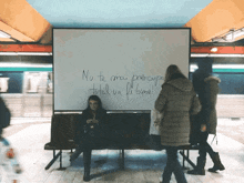 a woman sits on a bench in front of a large white board that says nu te mai preocupa total va fi bine