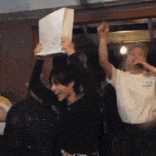 a group of people are raising their arms in the air while one man holds a piece of paper in his hand .