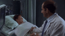 a doctor shakes hands with a patient who is laying in a hospital bed