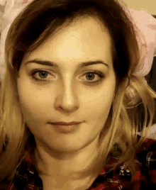 a woman wearing a plaid shirt looks at the camera