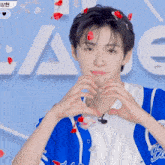 a young man in a blue shirt making a heart shape
