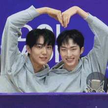 two young men make a heart with their hands