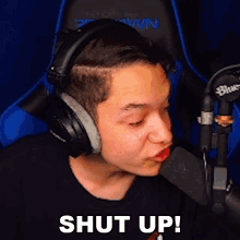 a man wearing headphones is talking into a microphone and says shut up