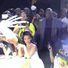 a woman in a white dress is sitting at a table surrounded by people .