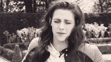 a black and white photo of a woman with her eyes closed and her mouth open .