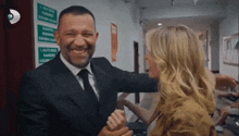 a man in a suit and tie is being hugged by a woman