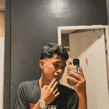 a young man taking a picture of himself in a mirror with a case that says x
