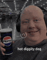 a bald man wearing headphones holds a pepsi cup