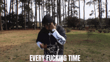 a man wearing headphones is standing in a park with the words every fucking time written on the ground