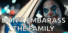a clown is driving a car with the words `` do n't embarrass the family '' written on the bottom .