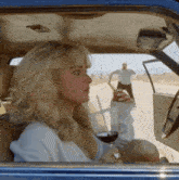 a woman in a car holds a glass of wine