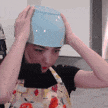 a woman is wearing an apron and holding a bowl on her head .