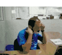 a man wearing a mask is sitting at a desk .