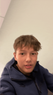 a young boy wearing a blue nike hoodie looks at the camera