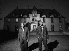 two men are standing in front of a large building