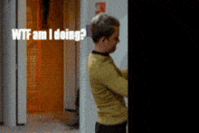 a man in a yellow shirt is standing in a hallway with the words " wtf am i doing " written above him