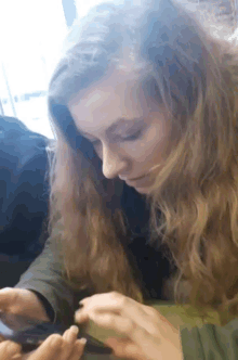 a woman with long blonde hair is looking at her phone