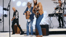 a man in a cowboy hat is playing a guitar in front of a microphone