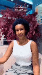 a woman wearing a white tank top with the name cengizhan on the bottom right