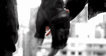 a black and white photo of a person holding another person 's hand in a city .