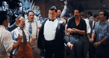 a man in a tuxedo is dancing in front of a crowd of people .