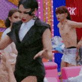 a man without a shirt is standing next to a woman in a black dress