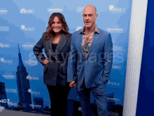 a man and a woman are standing in front of a wall that says wolf