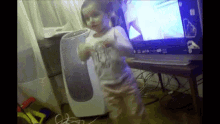 a little girl is dancing in front of a laptop that says windows on it