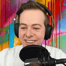 a man wearing headphones and a microphone is smiling .